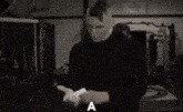 a man in a black shirt is standing in a room with the word może written on the bottom of his face .