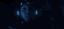a close up of a person 's face in a dark room with blue lights coming out of his ears .
