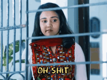 a woman behind bars with the word oh shit written on her shirt