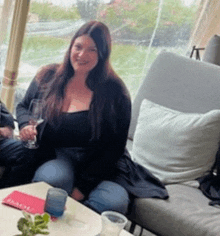 a woman is sitting on a couch holding a wine glass .