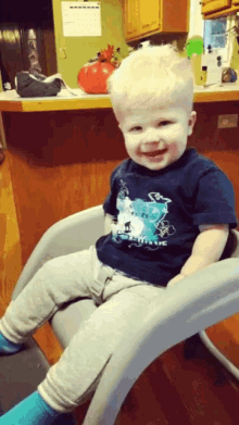 a little boy wearing a blue shirt with a polar bear on it is sitting in a high chair