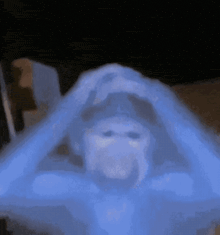 a person is covered in a blue blanket and a ghost is coming out of the blanket .