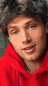 a young man wearing a red hoodie is smiling