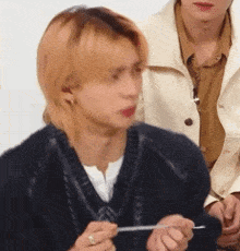 a young man with blonde hair is holding a piece of paper in his hand .