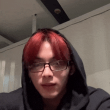 a man with red hair is wearing glasses and a hoodie