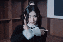 a woman in a black dress and white collar is pointing at something