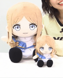 a woman holding a stuffed doll next to another doll