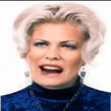 a woman with white hair and a blue turtleneck is making a face