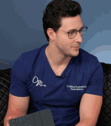 a man wearing glasses and a blue shirt that says dr. mikhail ivankovich d.o. family medicine