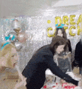 a group of women are standing around a cake in a room .