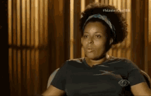 a woman in a black shirt is sitting in a chair with a cbs logo on her shirt