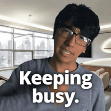 a man wearing glasses and a shirt that says " keeping busy "