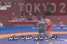two men are wrestling on a blue mat in front of a sign that says tokyo .