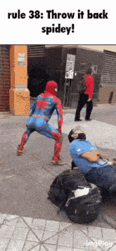 a man in a spiderman costume is standing next to another man in a blue shirt