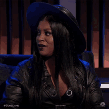 a woman wearing a hat and a leather jacket is sitting on a couch with the words songland written on the bottom