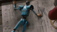 a blue puppet is sitting on top of a piece of paper with a drawing of a man on it