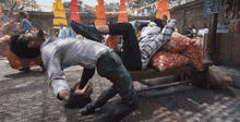 a man laying on another man 's back with a sign in the background that says ' chicken '