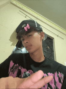 a young man wearing a black hat with a pink bow on his head