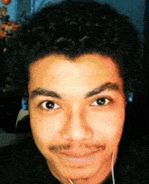 a young man with curly hair and a mustache is wearing headphones