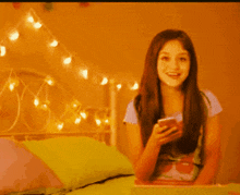 a girl is sitting on a bed looking at her cell phone