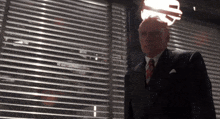 a man in a suit and tie is standing in front of a blind