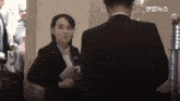 a woman in a suit is talking to a man in a suit in a room