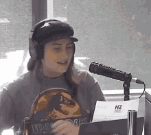 a woman wearing headphones and a jurassic park t-shirt is speaking into a microphone