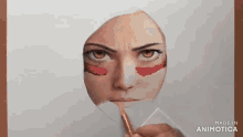 a person is drawing a woman 's face with red paint on her cheeks