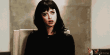 a woman is sitting in a chair making a funny face .