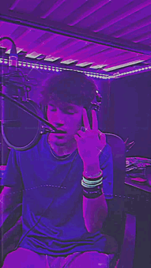 a man wearing headphones is giving the middle finger in front of a microphone