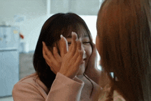 two women are touching each other 's faces and one has a ring on her finger