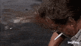a man is smoking a cigarette next to a shark in the water .