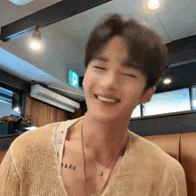 a man with a tattoo on his chest is smiling in a restaurant