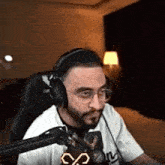 a man is wearing headphones and glasses while sitting in front of a microphone .