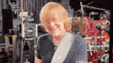 a man with a guitar strap that says apple on it is smiling