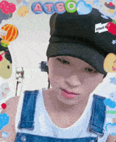 a boy wearing overalls and a hat with atbo on it