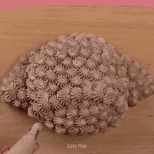 a cake with chocolate frosting is on a wooden cutting board with a pink background