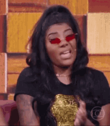 a woman wearing red glasses and a black shirt is making a funny face .