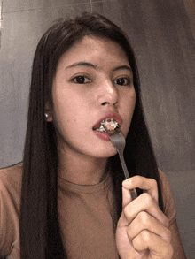 a woman with braces holds a fork in her mouth