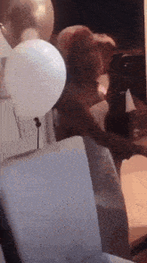 a woman is standing in a room surrounded by balloons and chairs