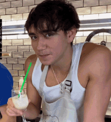 a man wearing an apron is holding a glass with a straw in it