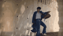 a man in a white shirt and blue pants is standing in front of a wall