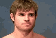 a shirtless man is making a funny face .