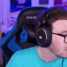 a man wearing glasses and headphones is sitting in a dxr chair .