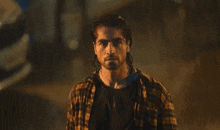 a man with long hair and a plaid shirt is standing in the rain
