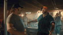 two men are standing in a pool hall talking