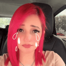 a woman with red hair is sitting in a car with tears coming out of her eyes