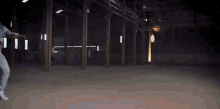 a person is standing in an empty warehouse with a light shining through the windows
