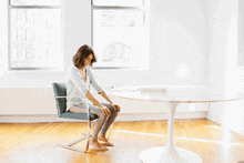 a woman sits in a chair in front of a white table