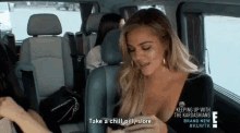 a woman is sitting in the back seat of a car talking to another woman while holding a cell phone .
